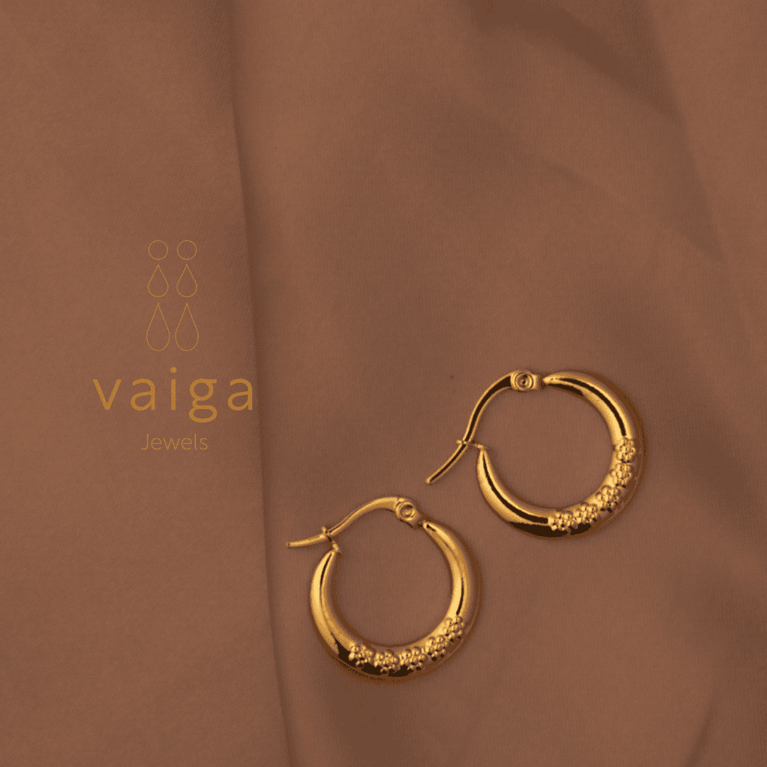 Gold-toned stainless steel textured hoop earrings design by Vaiga Jewels, modern luxury women's accessory on blush pink background.