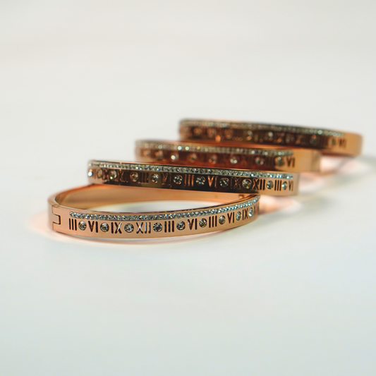 Stainless steel bracelets with roman numeral design stacked on a white surface