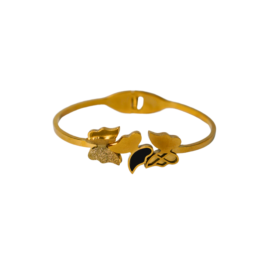A gold-toned bracelet featuring an elegant butterfly and floral design with a mix of textured, glossy, and black enamel details. The bracelet is displayed against a plain white background, highlighting its intricate craftsmanship and polished finish.