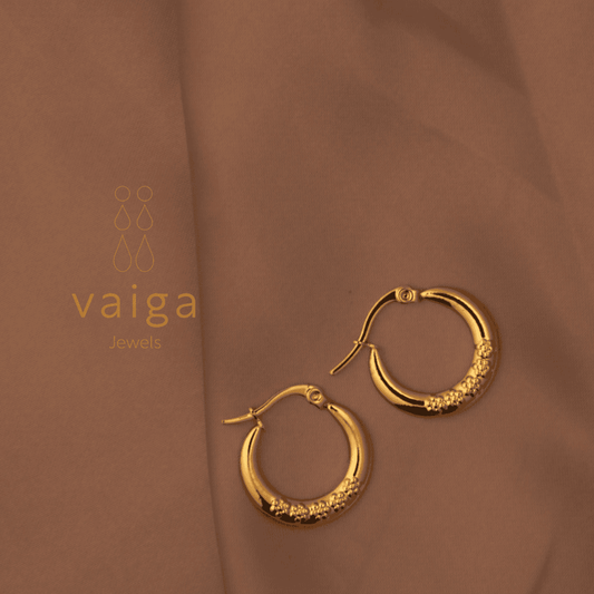 Gold-toned stainless steel  textured hoop earrings design by Vaiga Jewels, modern luxury women's accessory on blush pink background.