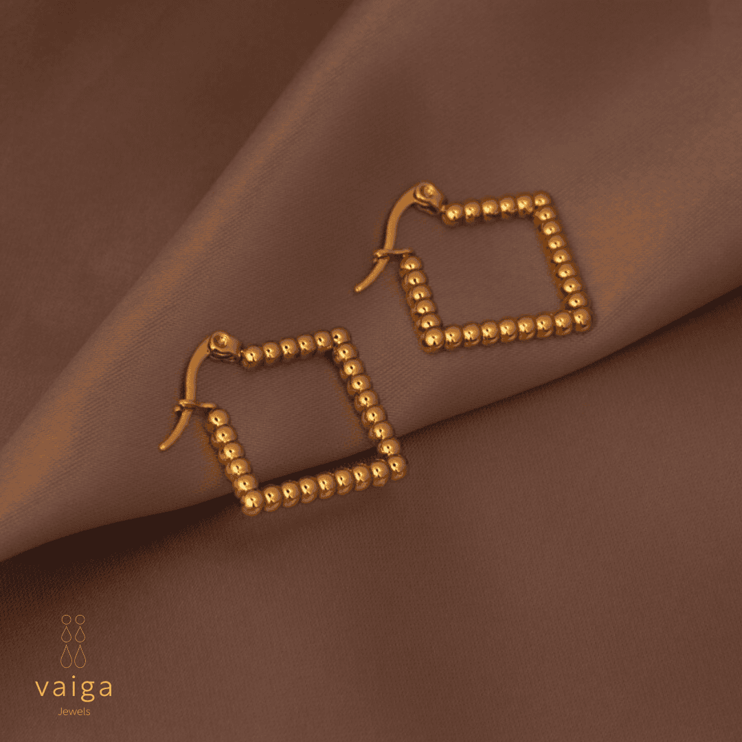 Gold-toned stainless steel textured square - shaped earrings by Vaiga Jewels, modern luxury women's accessory on blush pink background.