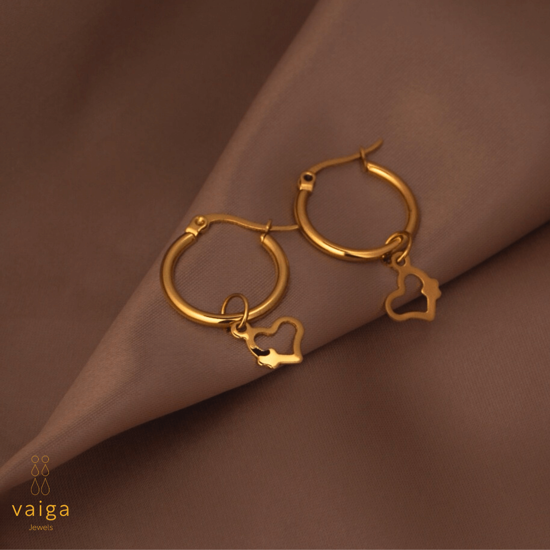 Gold-toned stainless steel hoop earrings with  by Vaiga Jewels, modern luxury women's accessory on blush pink background.