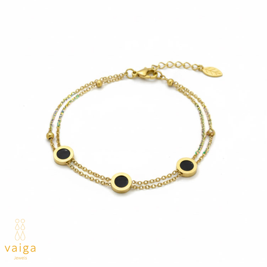 Gold bracelet with black stones on a white background, branded 'vaiga'.