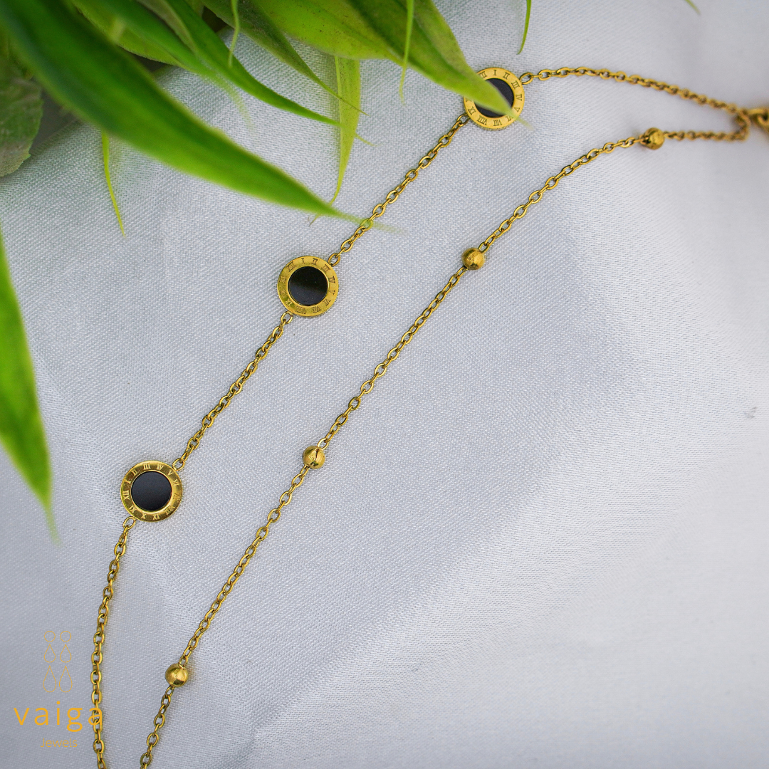 Gold chain necklace with black stones on a white fabric background